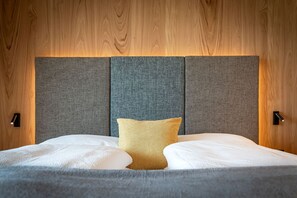 A bed with a grey headboard, a single yellow pillow, and two bedside lamps. - Knöspele Brennerei & Genuss-Apartments Fructum (Brixen)