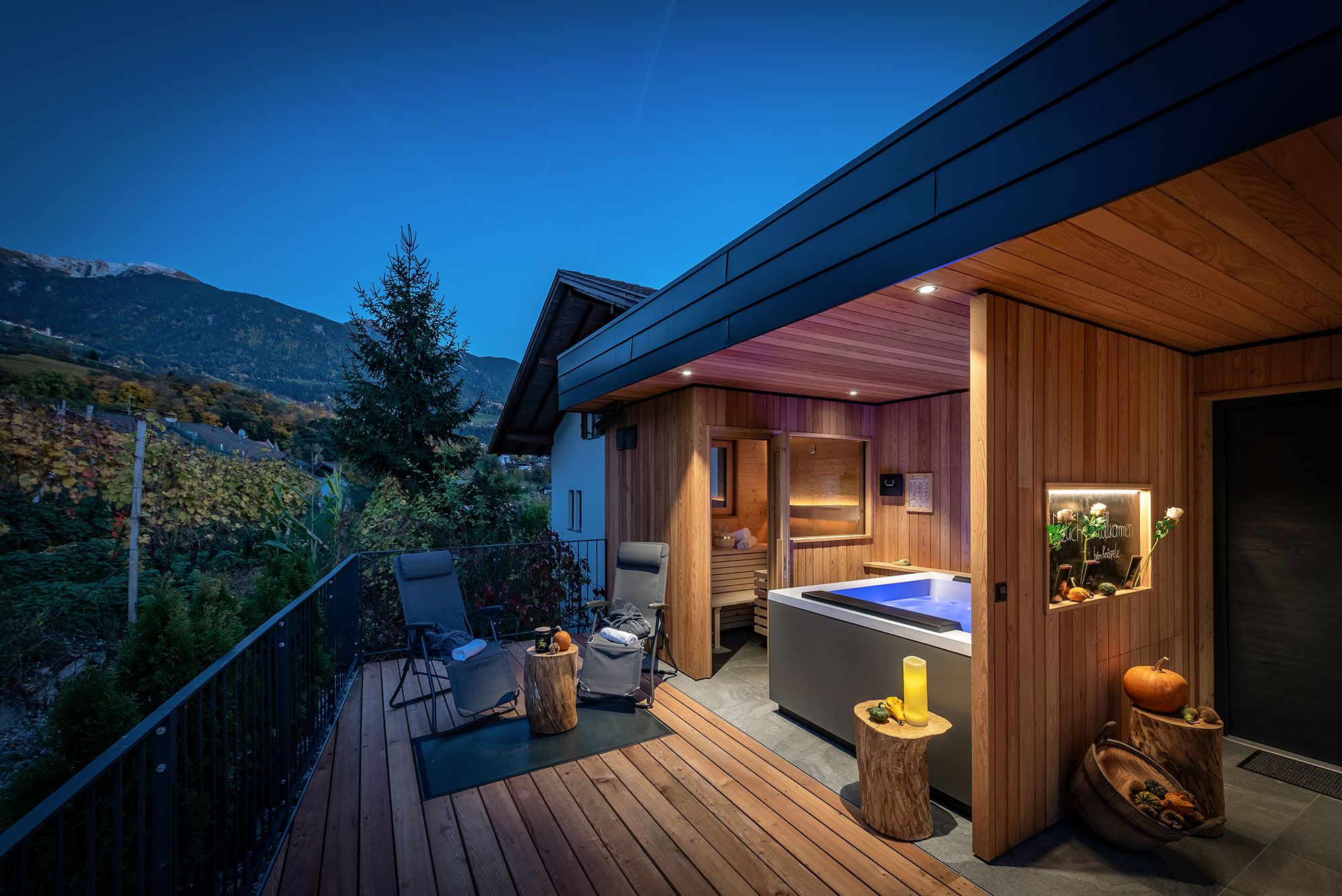A modern outdoor deck with a hot tub, wooden deck, and a view of the mountains.