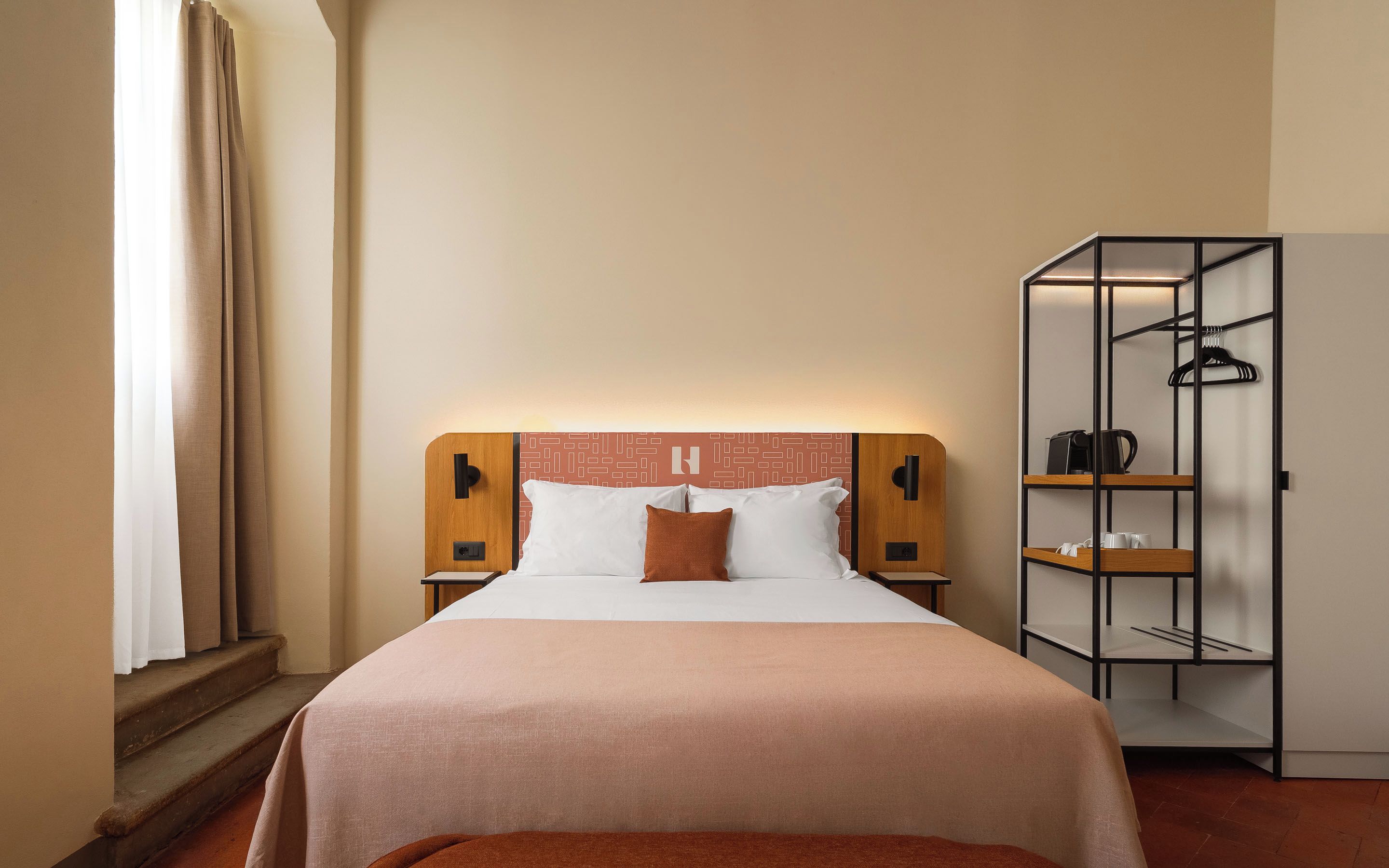 A hotel room with a bed, a wardrobe, and a nightstand.