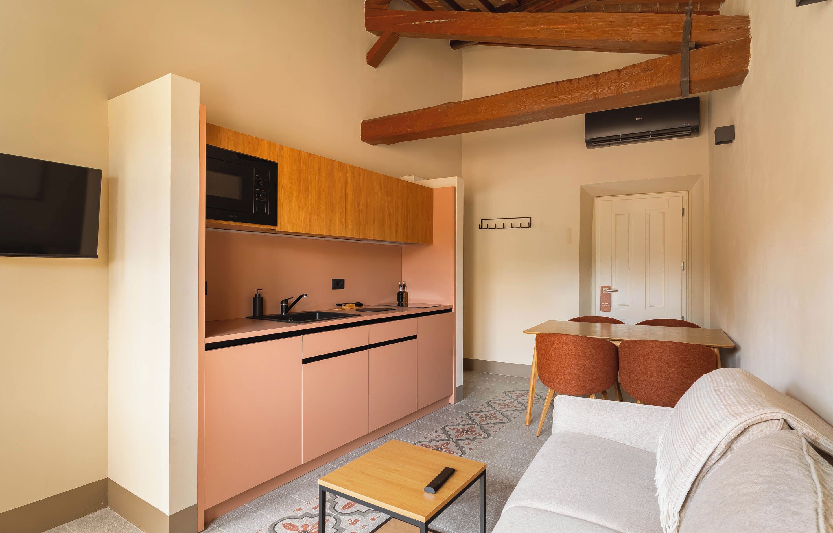A compact living space with a kitchenette, a dining area, and a seating area with a sofa and chairs.