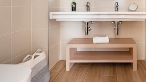 Un baño moderno con un espejo grande, un lavabo con una toalla y una zona de ducha.
