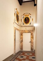 Un pasillo con una puerta blanca, pared de mármol y piso con diseño.