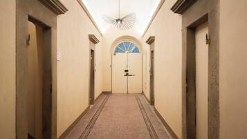 A hallway with a patterned carpet, a ceiling fan, and a door with a frosted glass window at the end.