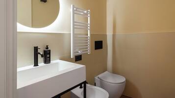 A modern bathroom with a white sink, black faucet, and a white toilet.