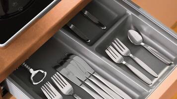 A kitchen drawer with utensils and a kettle.