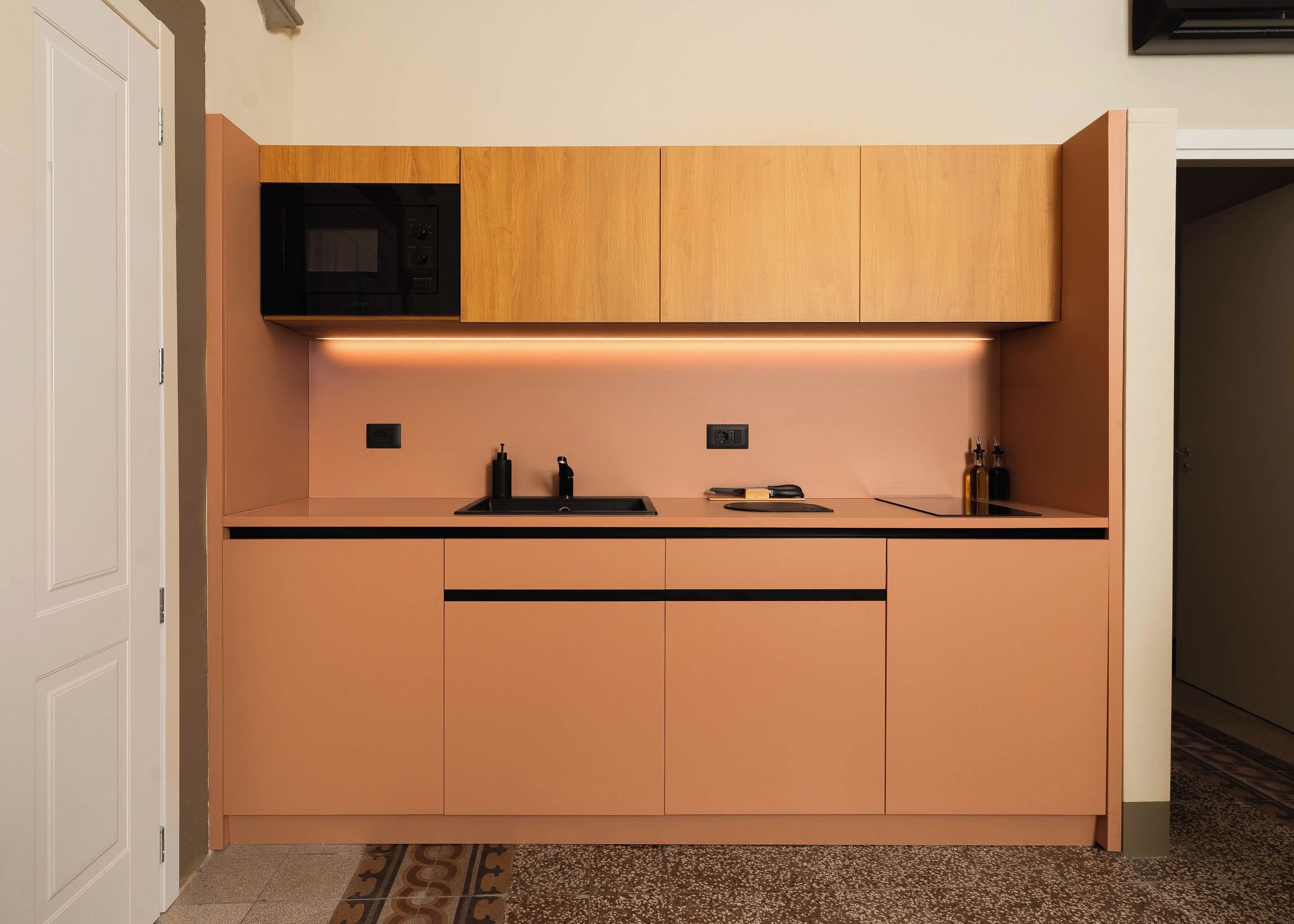 A compact kitchen with wooden cabinets, a microwave, and a countertop with a sink.