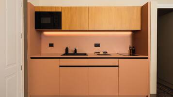 A compact kitchen with wooden cabinets, a microwave, and a countertop with a sink.