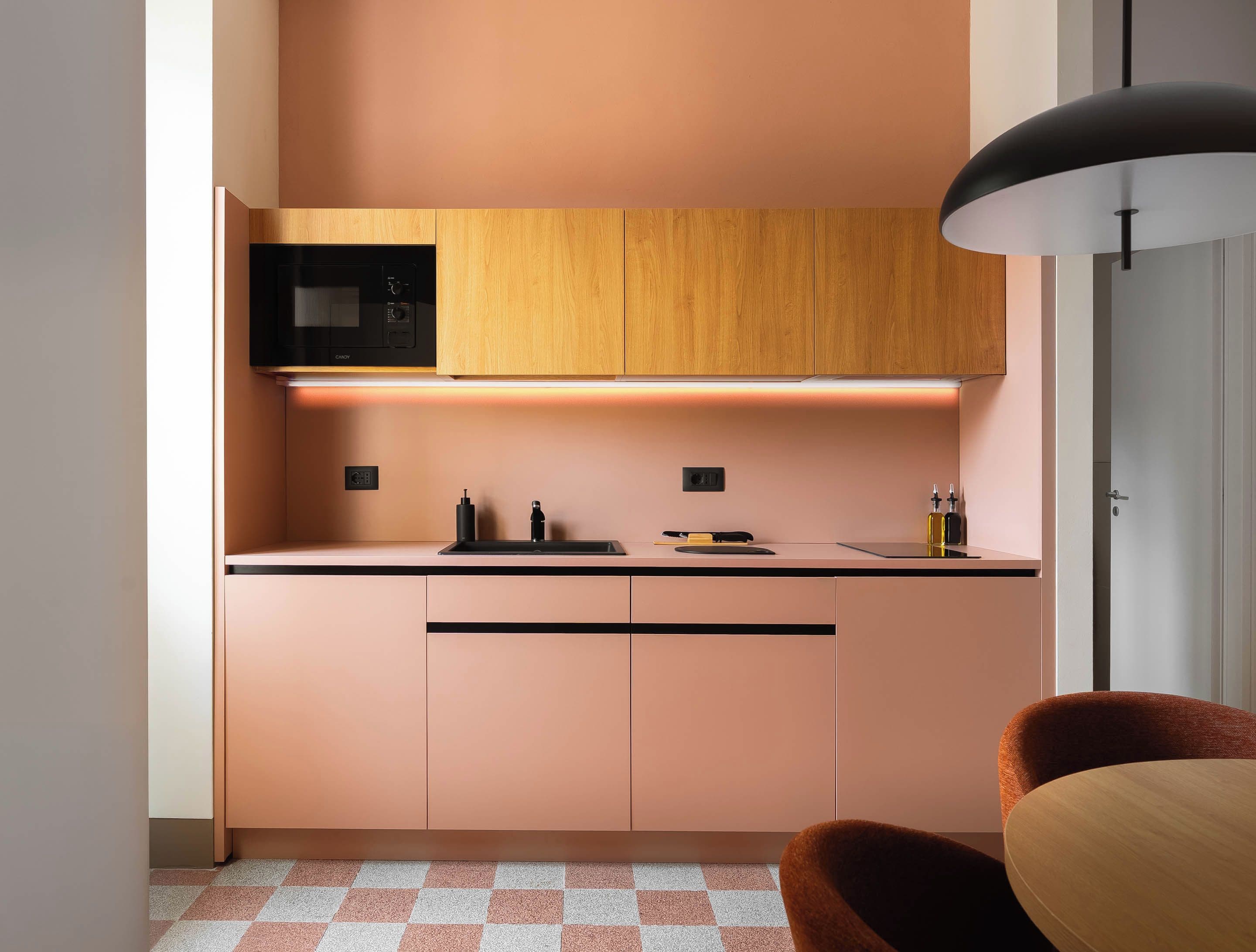 Una cocina moderna con armarios de madera, microondas y encimera negra.