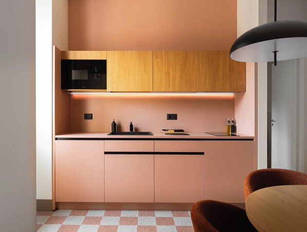 A modern kitchen with wooden cabinets, a microwave, and a black countertop.