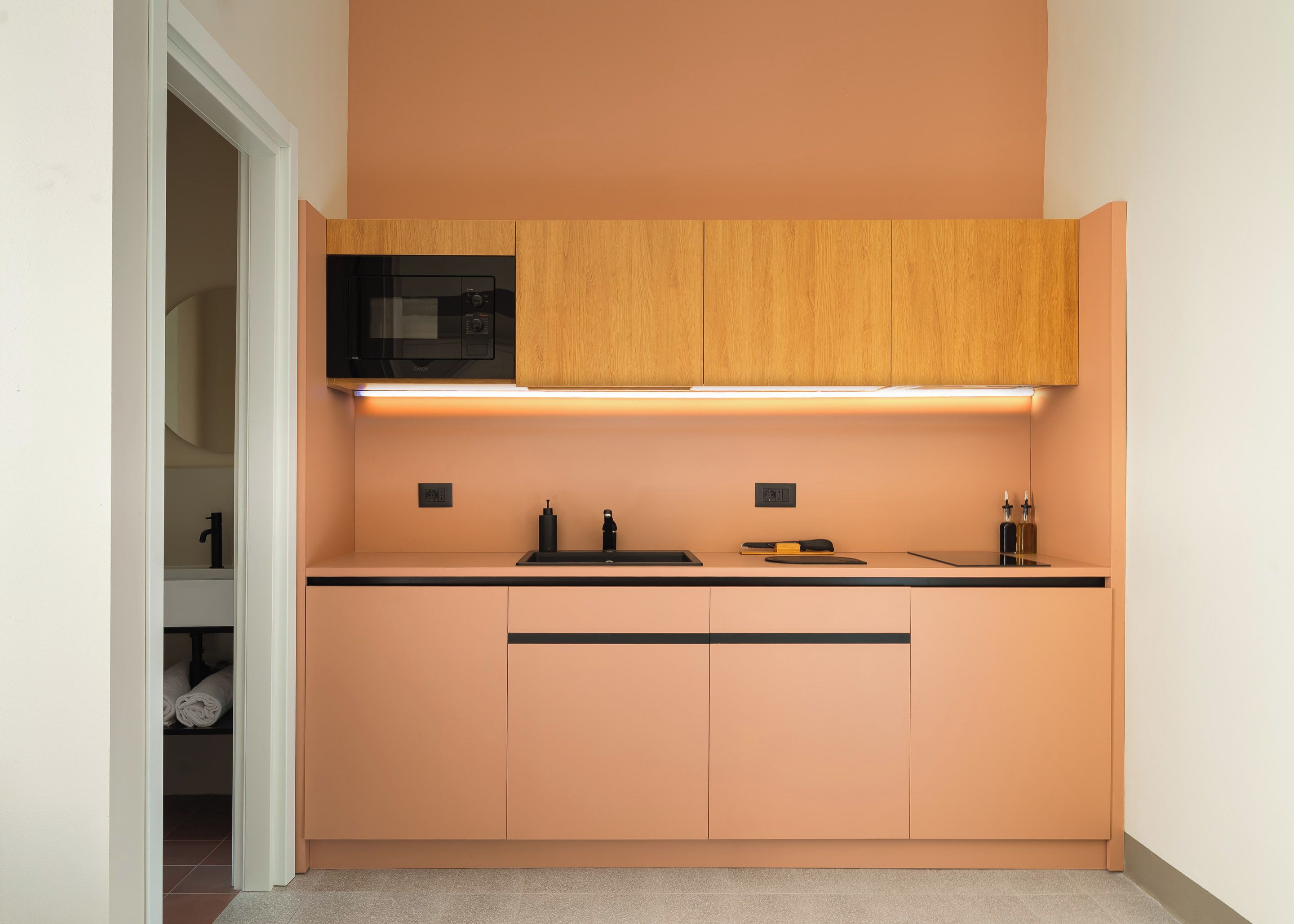 A compact kitchen with a microwave, a sink, and wooden cabinets.