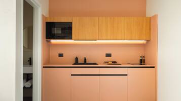 A compact kitchen with a microwave, a sink, and wooden cabinets.