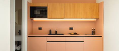 Una cocina compacta con microondas, un lavamanos y armarios de madera.