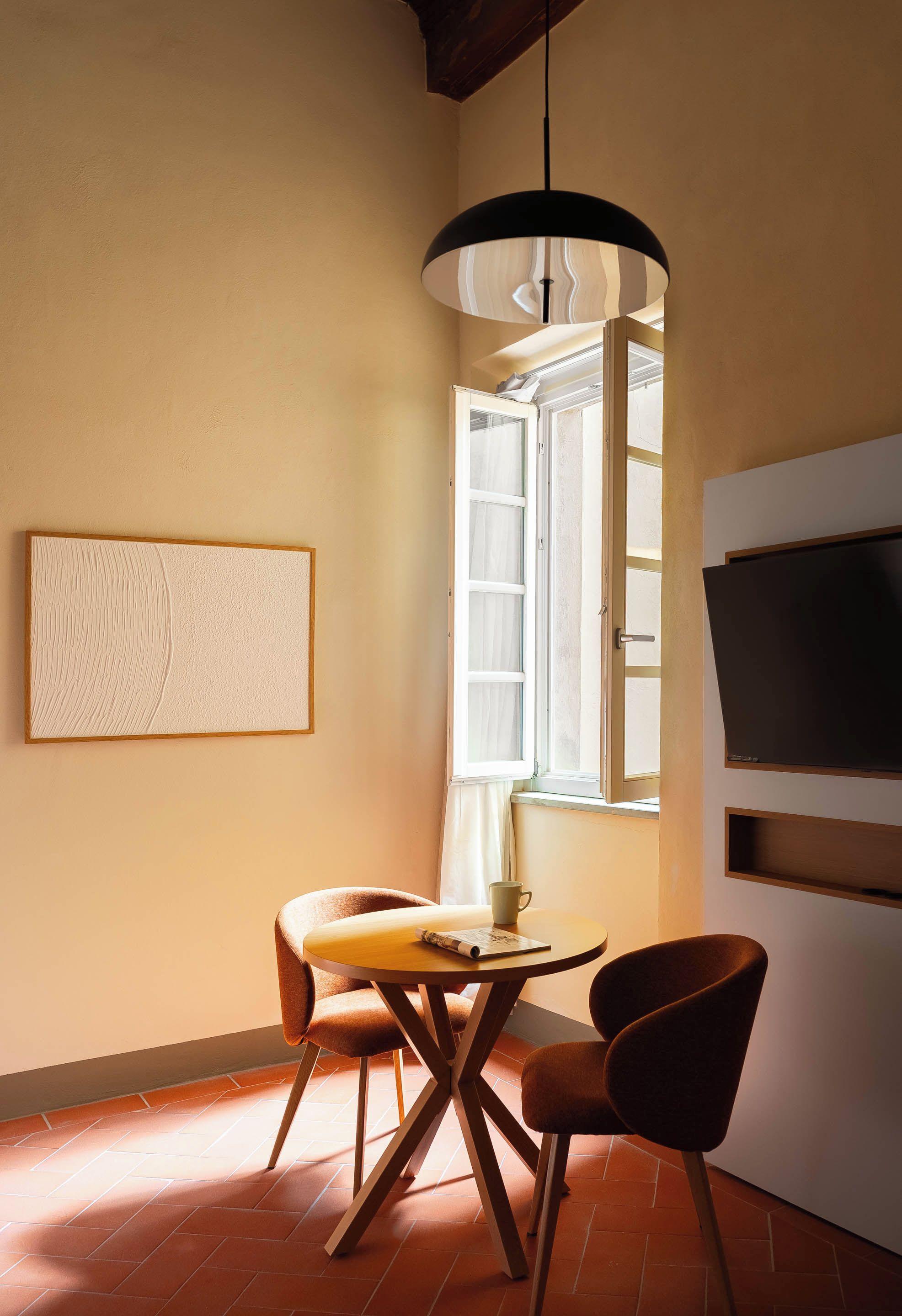 Une pièce confortable avec une table à manger, des chaises, un téléviseur et une fenêtre avec des rideaux.
