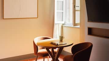 Une pièce confortable avec une table à manger, des chaises, un téléviseur et une fenêtre avec des rideaux.