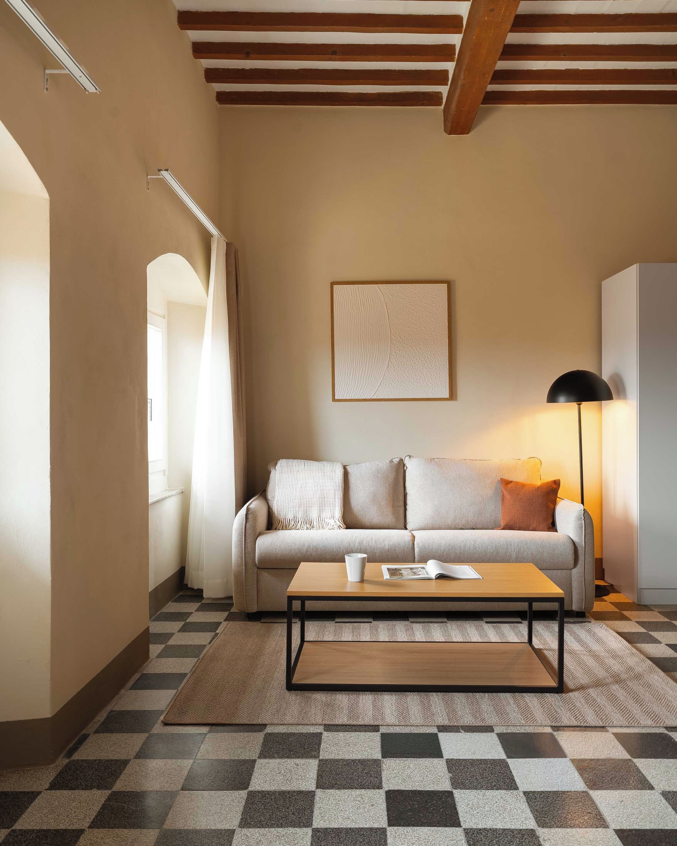 Una sala de estar acogedora con piso de cuadros, un sofá, una mesa de centro y una lámpara.
