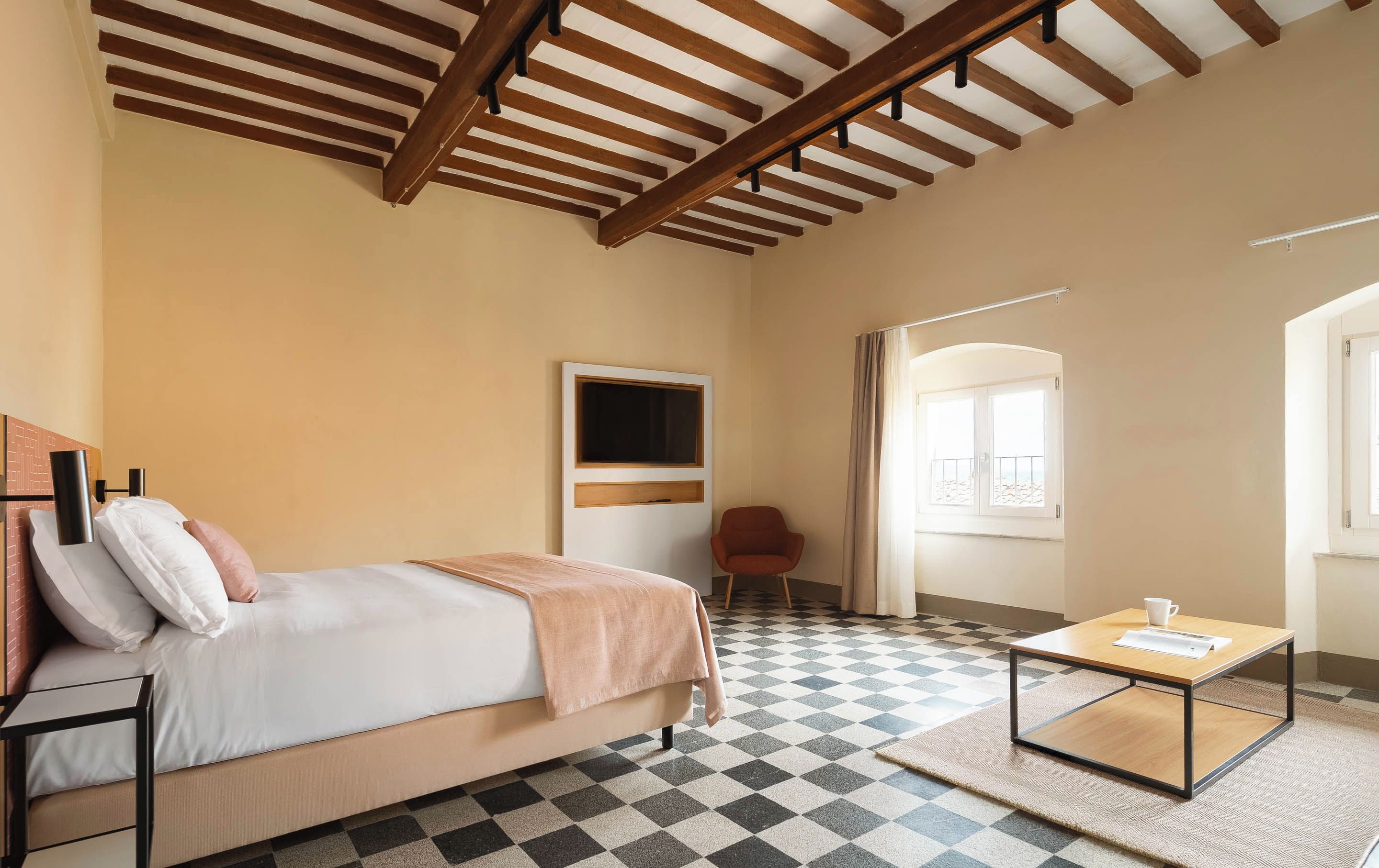 Een hotelkamer met een bed, een stoel, een tafel en een groot raam.