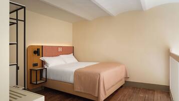 A single bed with a wooden headboard, a bedside table, and a wall-mounted light fixture.