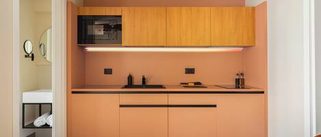 A compact kitchen with wooden cabinets, a black microwave, and a countertop with a sink.