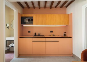 Una cocina compacta con armarios de madera, un microondas negro y una encimera con fregadero.