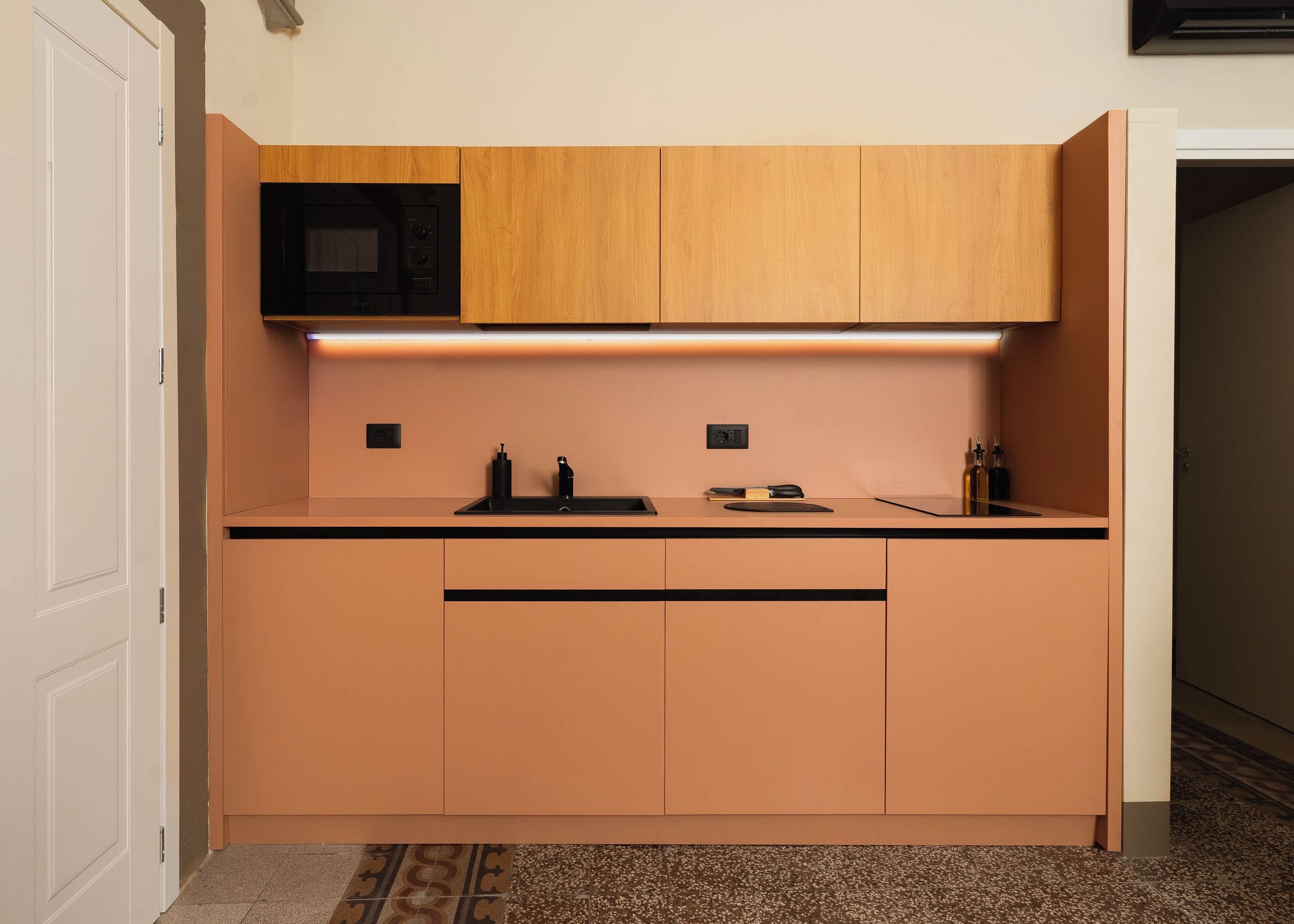 A compact kitchen with a microwave, a sink, and wooden cabinets.