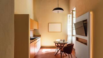 Una cocina compacta con comedor, una lámpara colgante y una obra de arte enmarcada en la pared.