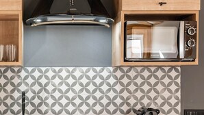 Una cocina con microondas, hervidor de agua y un salpicadero decorado.