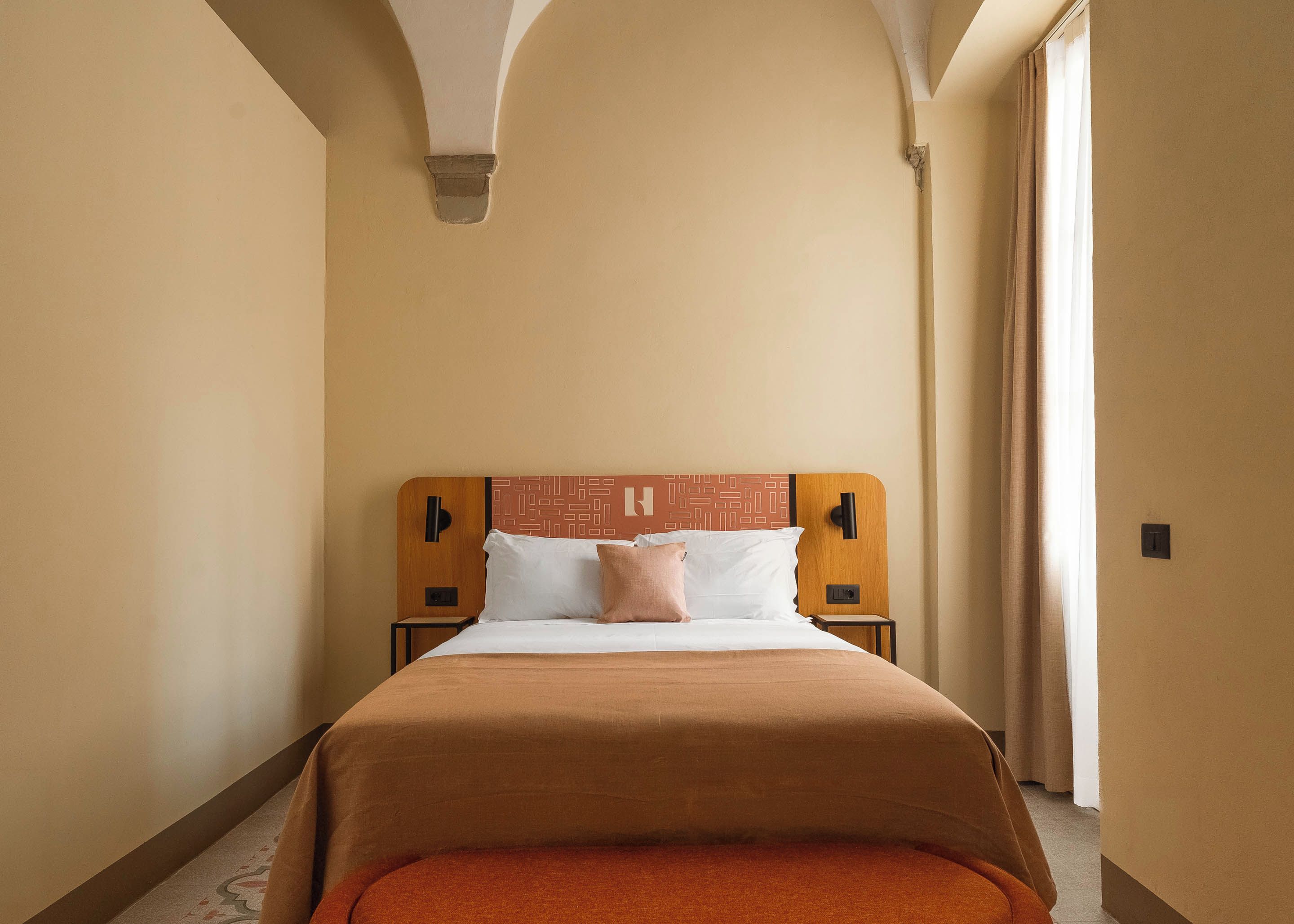 Une chambre d’hôtel avec un grand lit, une tête de lit en bois et une vue sur l’extérieur.