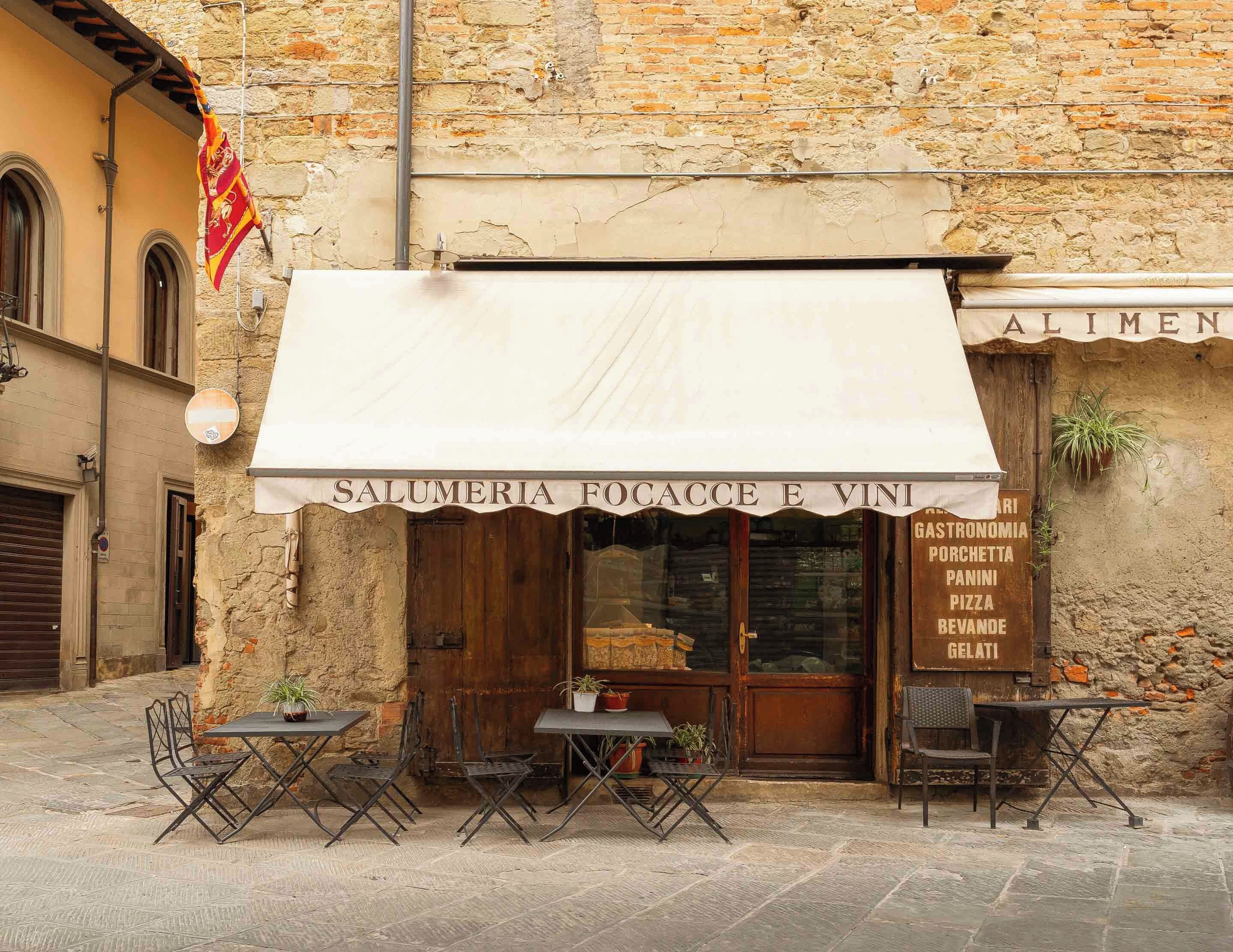 A restaurant named 'SALUMERIA FOCACCE E VINI' with outdoor seating and a stone facade.