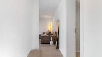 A hallway leading to a living area with a sofa, a lamp, and a mirror.
