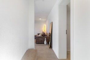A hallway leading to a living area with a sofa, a lamp, and a mirror.