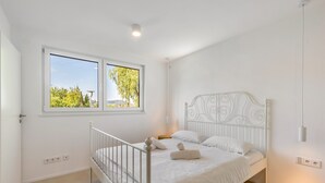 Ein Schlafzimmer mit einem Einzelbett, einem Fenster mit Blick auf Grünflächen und einer weißen Decke.