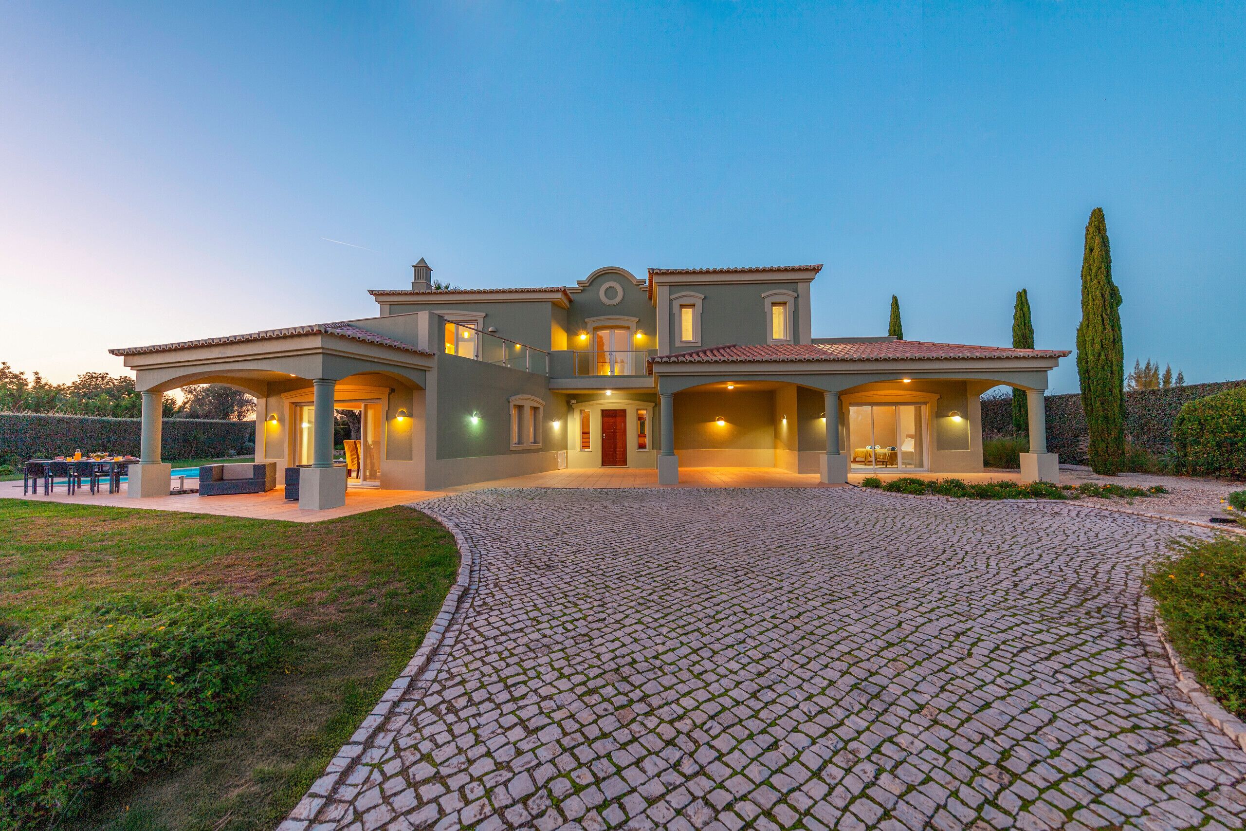 A large, two-story house with a paved driveway and outdoor seating area.