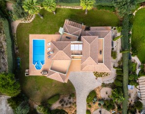 Vue aérienne d’une propriété dotée d’une piscine, d’un espace de détente extérieur et d’un jardin aménagé.