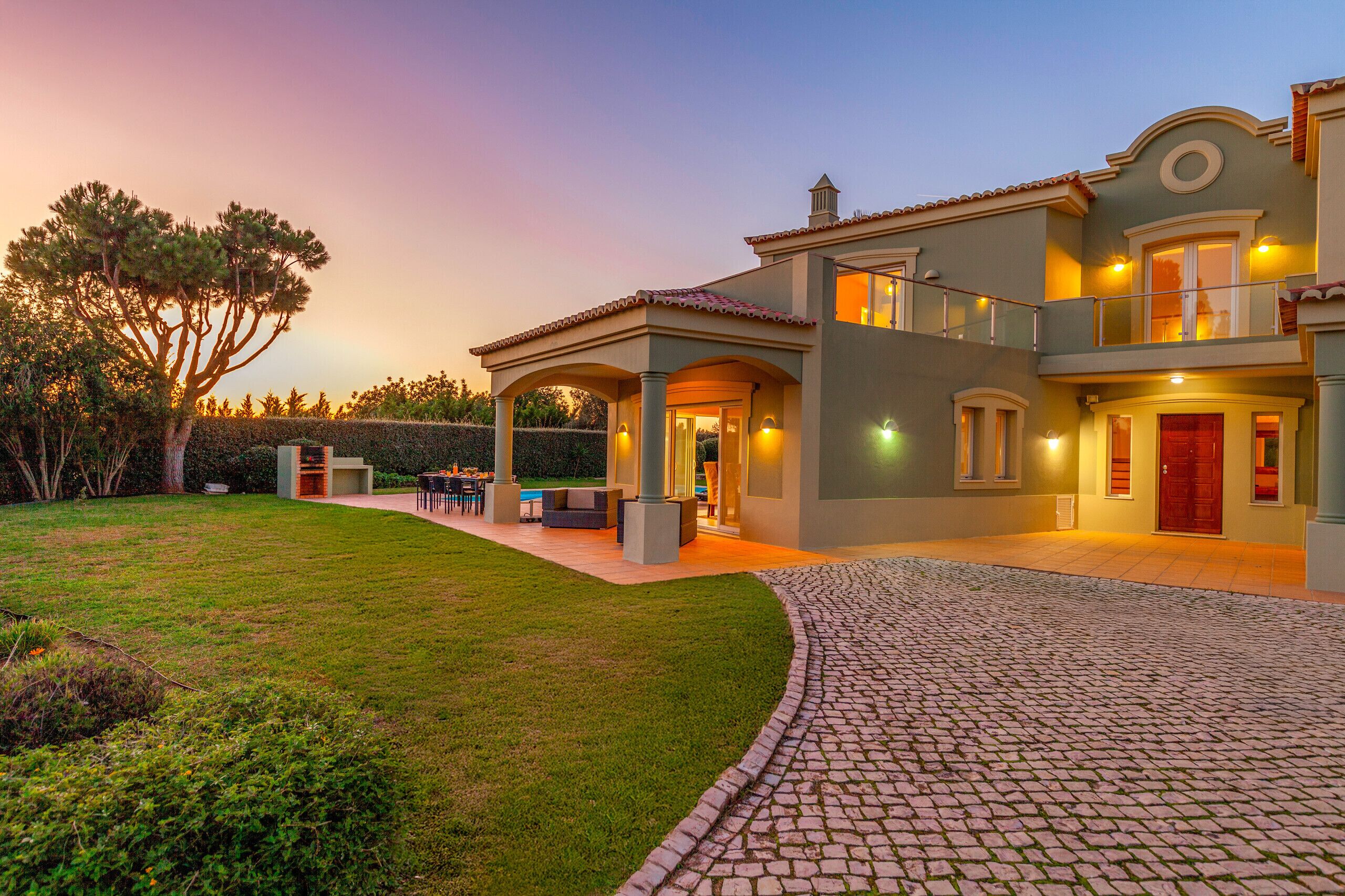 Une maison à deux étages dotée d’un patio couvert, d’une piscine et d’une pelouse bien entretenue.
