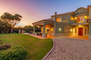 Une maison à deux étages dotée d’un patio couvert, d’une piscine et d’une pelouse bien entretenue.
