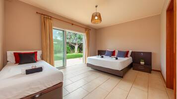 A modern hotel room with two beds, a large sliding glass door to the outdoors, and a ceiling light fixture.
