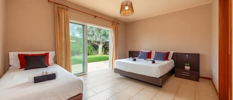 A modern hotel room with two beds, a large sliding glass door to the outdoors, and a ceiling light fixture.