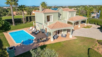 A large house with a swimming pool, outdoor seating, and a view of the surrounding landscape.