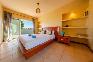 A modern hotel room with a large bed, a bedside table, a nightstand, a bookshelf, and a sliding glass door to the balcony. - Villa w/ Heatable Pool & Built-in Jacuzzi (Carvoeiro)
