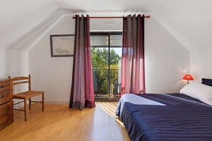 Een slaapkamer met een bed, een stoel, een nachtkastje, een lamp en een raam met gordijnen.