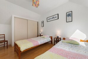 Een slaapkamer met twee enkele bedden, een kledingkast, een bureau en een stoel.