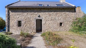 A stone building with a sloped roof, a central entrance, and two small windows on the upper floor. - Gîte Les Pâturages, Larmor-Plage: Private Terrace, Garden, and Wi-Fi (Larmor-Plage)