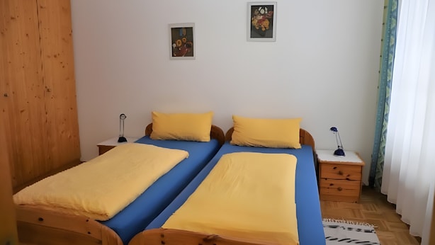 Een tweepersoonsbed met twee kussens, een nachtkastje, een lamp en een klein schilderij aan de muur.