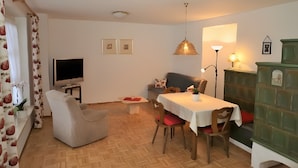 Een woonkamer met een televisie, een eettafel en een bank.