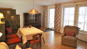 Een eethoek met een tafel, stoelen, een bank en een televisie.