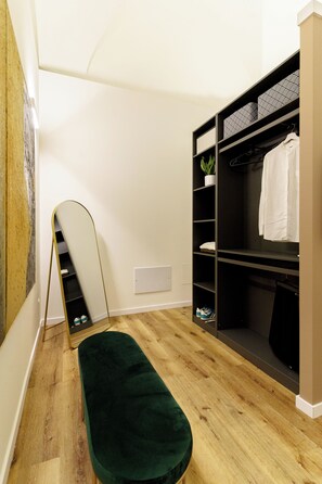 A room with a wooden floor, a green bench, a black shelving unit with patterned cushions, and a white wall. - Charming suites nestled among art, the historic center, and the sea (Catania)