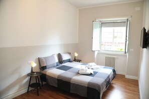 A bedroom with a bed, two bedside tables, a window with blinds, and a radiator. - A da Sora Valè Boutique Apartment - Vatican & Metro A (Roma)