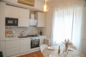 Una cocina moderna con gabinetes blancos, microondas integrado y estufa a gas.
