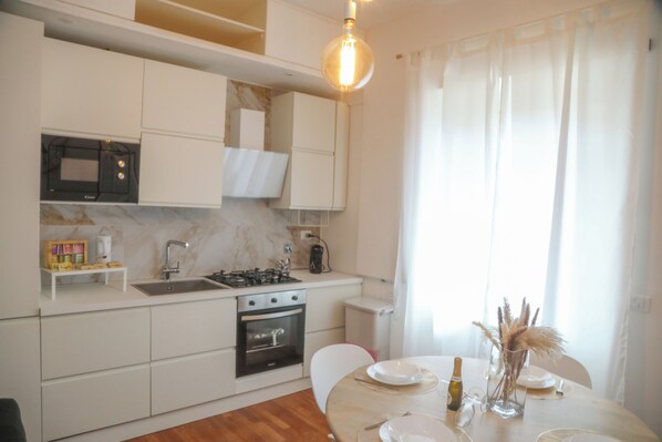 Una cucina moderna con mobili bianchi, un forno a microonde integrato e un piano cottura a gas.