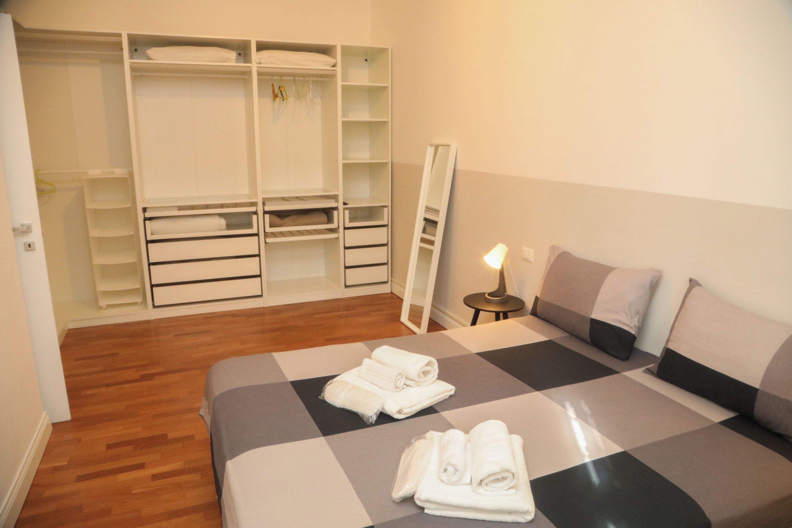 Ein Schlafzimmer mit einem Bett, einem Kleiderschrank und einem Nachttisch mit Lampe.